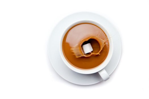 Sugar falling in a coffee cup against white background