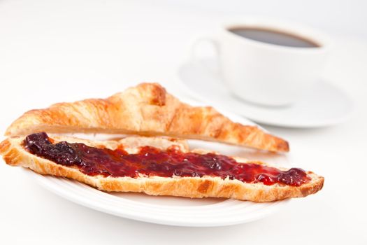 Croissant placed in front of a coffee cup on a table