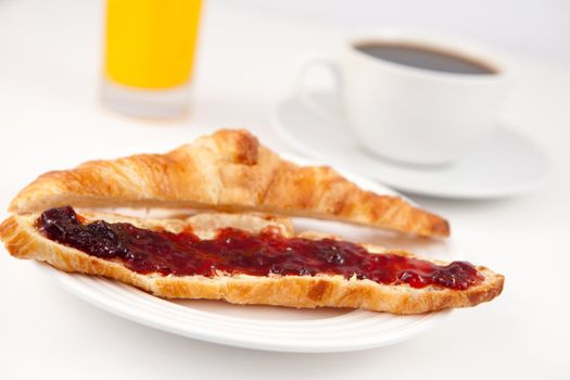 Coffee and orange juice behind a croissant on a table