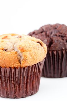 Close up of two fresh baked muffin and a blurred chocolate muffin against a white background