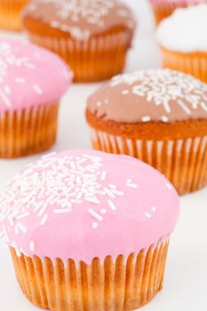 Close up of many muffins with icing sugar against a white background