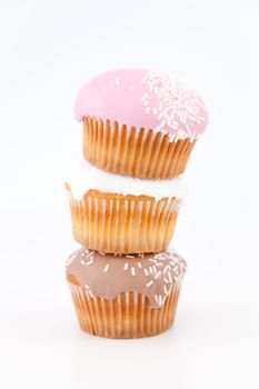 Three muffins with icing sugar piled up against a white background