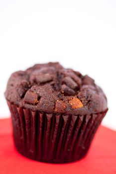 Dark chocolate muffin on a red table against a white background