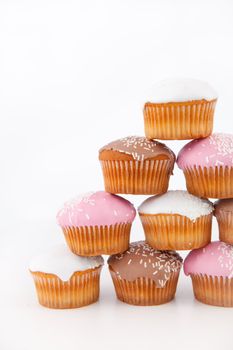 Many muffins with icing sugar placed in pyramid against a white background