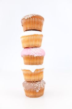 Five muffins with icing sugar piled up against a white background