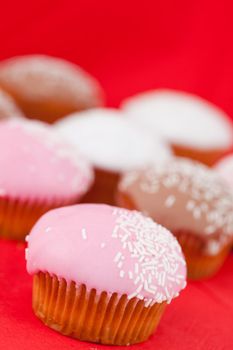 Many muffins with icing sugar on a red tablecloth 