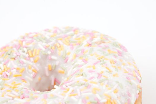 Close up on doughnut with multi coloured icing sugar against a white background