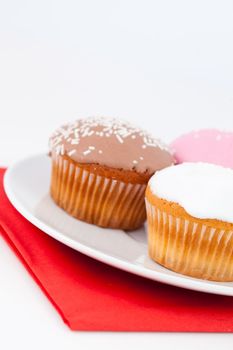 Three cupcakes on a white plate against a white baCKGROUND