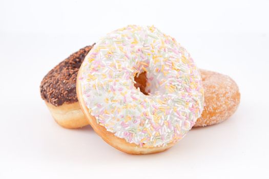 Three doughnuts with icing sugar against a white background