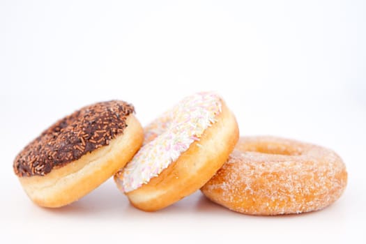 Three doughnuts with icing sugar lined up against a white background
