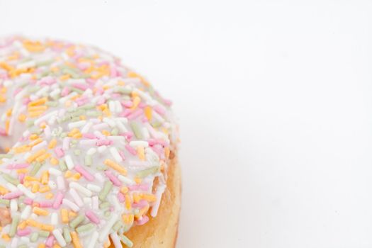 Close up of a doughnut with multi coloured icing sugar against a white background