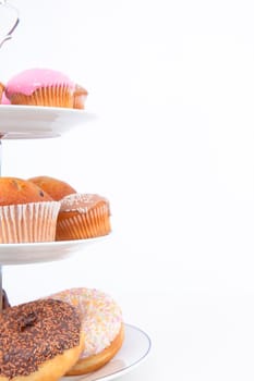 Close up of many cakes placed on three white plates against a white background