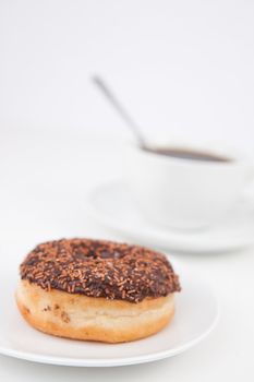 Chocolatedoughnut and a cup of coffee on white plates against a white background