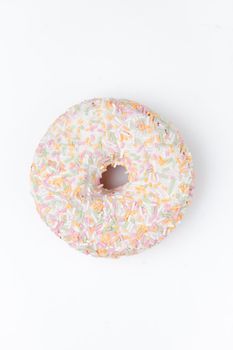 Extreme close up of a doughnut with multi coloured icing sugar against a white background