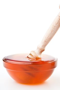 Honey dipper in a honey bowl against a white background