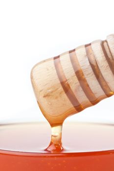 Close up of honey dipper on the top of a bowl against a white background