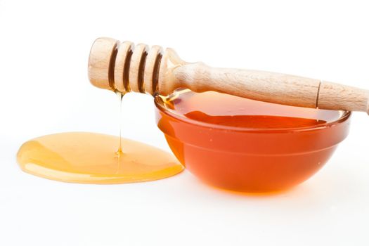 Thin honey trickle spilling on the floor against  a white background