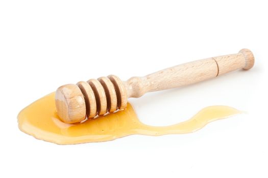 Honey dipper on the floor spilling honey against a white background