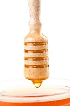 Honey drop on the top of a honey bowl against a white background