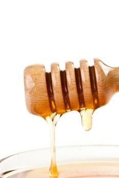 Honey trickle on the top of a honey full bowl against a white background