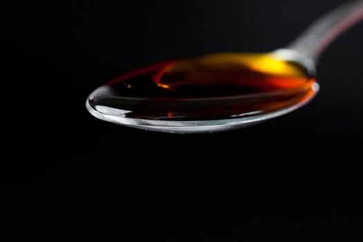 Full honey spoon against a black background