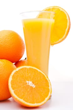 Pile of oranges near a glass of orange juice against white background