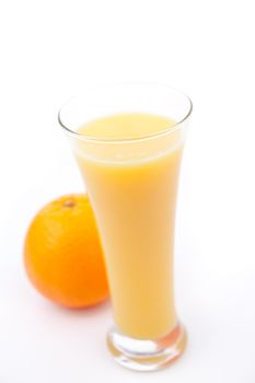 Orange behind a full glass of orange juice against white background