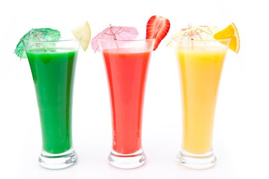 Fruit pieces and cocktail umbrella in a row of glasses against white background