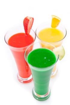 Three glasses full of fruit juice with fruits pieces against white background