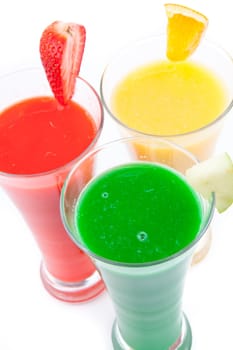 Fruits pieces placed on full glasses against white background