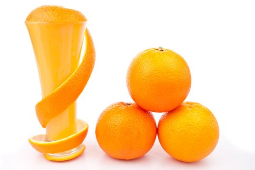 Orange peel wrapped around a glass near a pile of oranges against white background