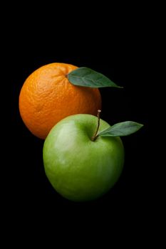 Orange and apple fruits against a black background