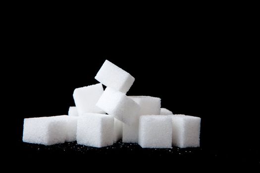 Sugar lumps piled up together against a black background