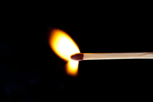 Horizontal match set on fire against a black background