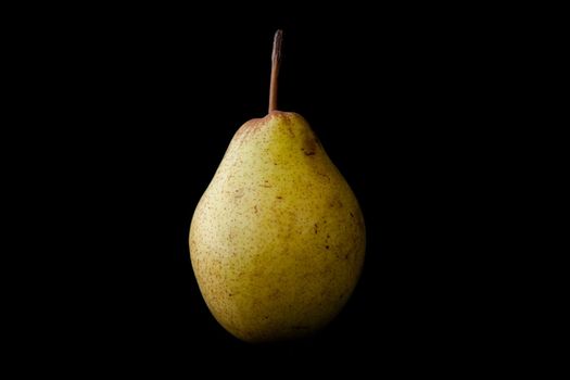 Green pear against a black baclground