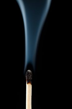 Smoking consumed match against a black background