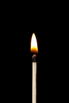 Vertical match on fire against a black background