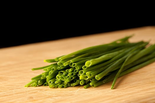 Many stands of chive against a black background