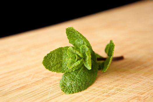Mint on a chopping board against a black background