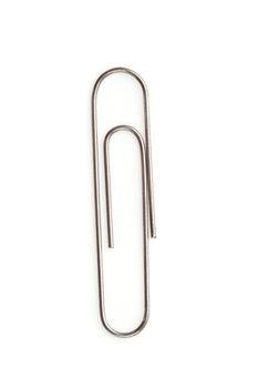 Close up of a grey paperclip on the floor against a white background