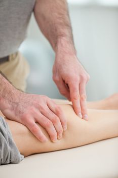 Physiotherapist pressing the calf of a patient in a room