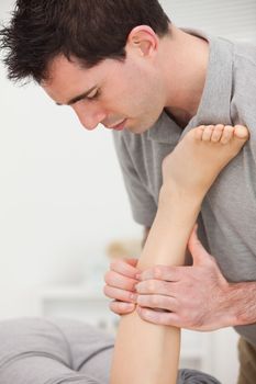 Woman lying while a physiotherapist is manipulating her leg indoors