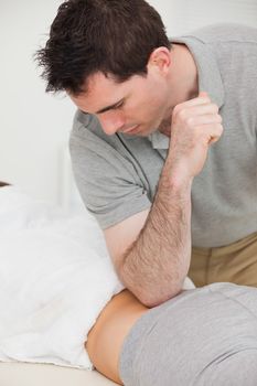 Physiotherapist massaging the back of a woman with his elbow in a room