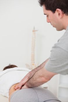 Physiotherapist massaging the lower part of the back of his patient in a room