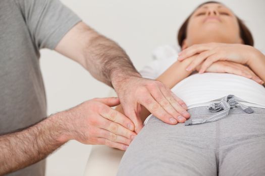 Woman lying while a physiotherapist massaging her thigh in a room