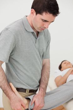 Physio stretching the leg of a woman while looking at her foot in a room