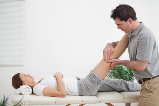 Physiotherapist massaging a leg while placing it on his shoulder in a room