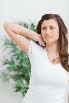 Woman standing while placing her hand on her neck in a room