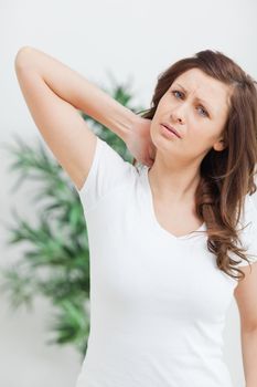 brunette standing while placing her hand on her neck in a room