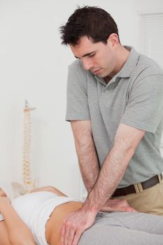 Serious physiotherapist manipulating the pelvis of a patient in a room